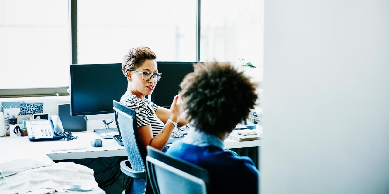 Businesswoman in discussion with businessman at office workstation